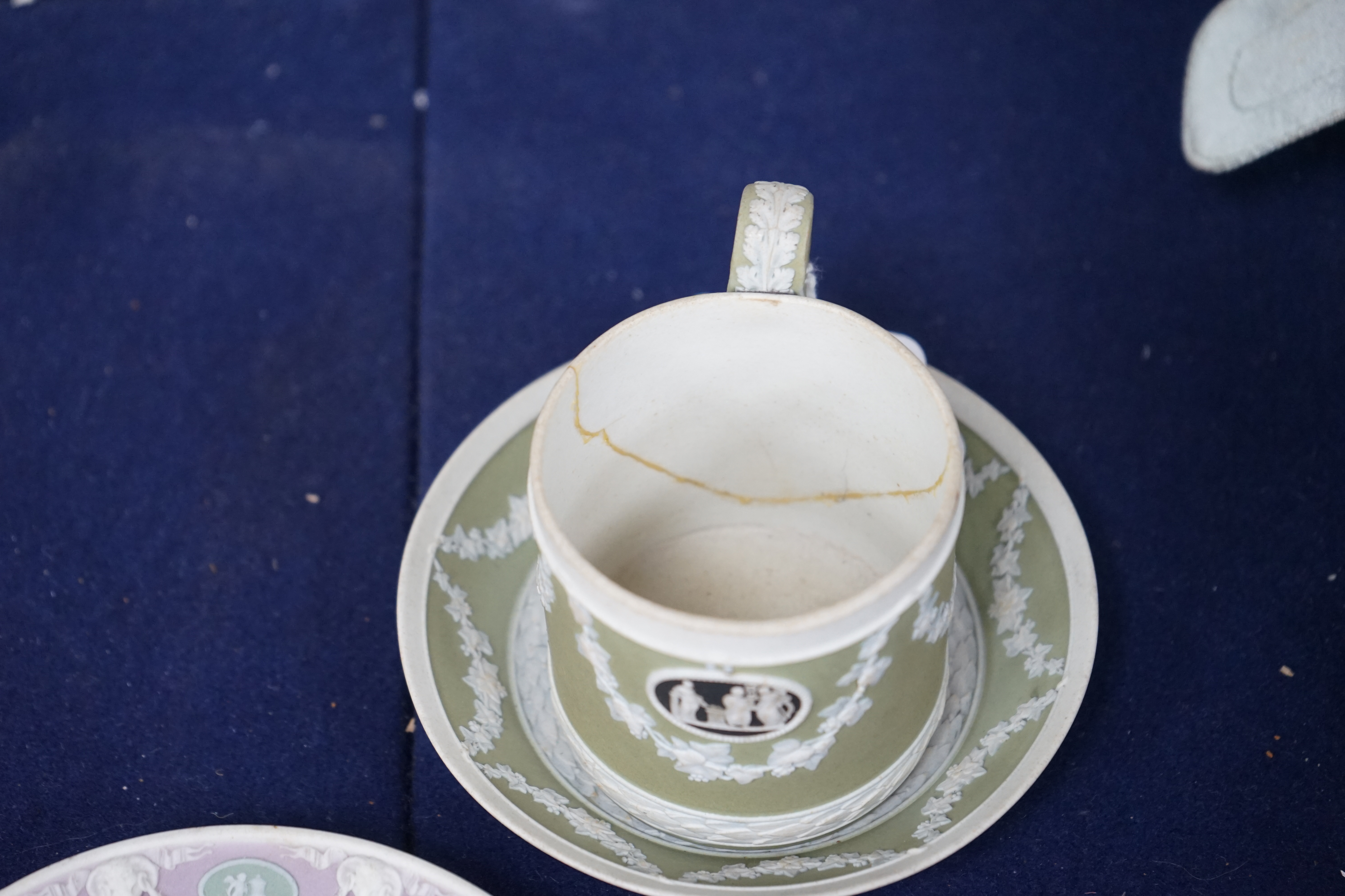 A Wedgwood three colour, green ground jasper cup and saucer and a single lilac ground saucer, early 19th century, 13.5cm. Condition - poor